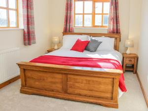 a bedroom with a large wooden bed with red sheets at Old Hall Barn 2 in Church Stretton