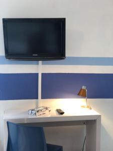 een bureau met een televisie aan een muur met een stoel bij Enzo Hotels Neufchâteau by Kyriad Direct in Neufchâteau