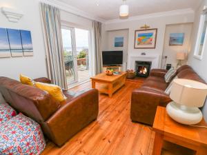 a living room with leather furniture and a fireplace at Mount View Cottage in Marazion
