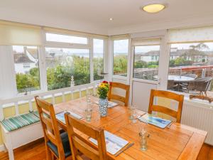 ein Esszimmer mit einem Holztisch und Fenstern in der Unterkunft Mount View Cottage in Marazion