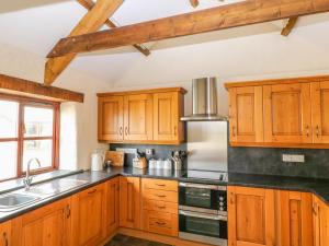 una cocina con armarios de madera y encimeras negras en Maerdy Cwtch, en Haverfordwest