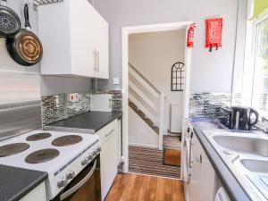 a kitchen with a stove top oven next to a sink at River Cottage in Port Talbot