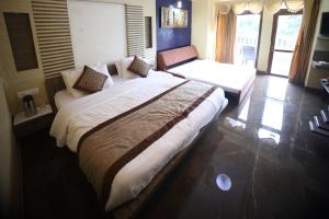 een slaapkamer met een groot bed en een bank bij The Byke Heritage Matheran in Matheran