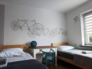 a bedroom with two beds and a desk with two bikes on the wall at APARTAMENT 16 in Zamość