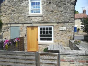 a stone house with a yellow door and a bench at May Cottage in Scarborough