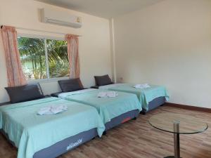 two beds in a room with a table and a window at แสงหิรัญ บีช รีสอร์ท in Pran Buri +38 photos