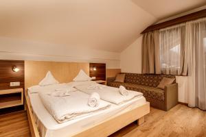 a bedroom with a large bed and a couch at Hotel Klammer in Vipiteno