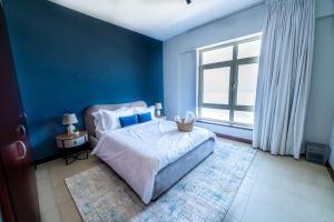 ein blaues Schlafzimmer mit einem Bett und einem Fenster in der Unterkunft Mabaat - Beach Tower - Building B - 251 in King Abdullah Economic City