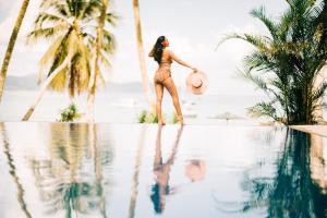 kobieta w bikini stojąca obok basenu w obiekcie Holiday Suites Port Barton w mieście San Vicente