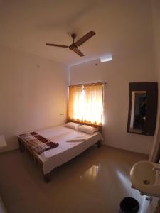 1 dormitorio con 1 cama y ventilador de techo en Aikya homestay, en Gokarna