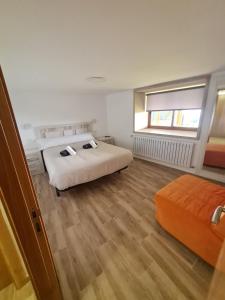 a bedroom with two beds and an orange couch at Casa Fondo de Vila in Chantada