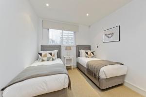 1 dormitorio con 2 camas y ventana en Veeve - Chelsea Bridge Wharf en Londres