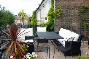 a patio with a black table and chairs and plants at Veeve - King's Road Roof Terrace in London