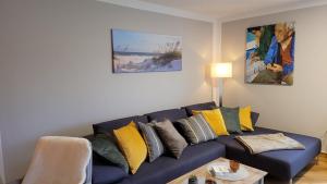 a living room with a blue couch with yellow pillows at Fewo Heimathafen 188 in Petersdorf auf Fehmarn