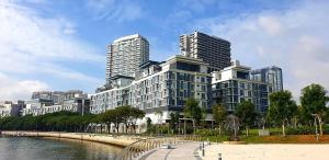 a large building next to a river with tall buildings at Trinidad Suites Johor, Trademark Collection by Wyndham in Nusajaya