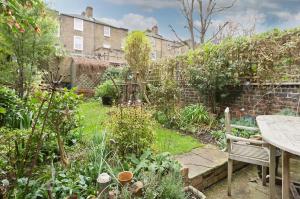 a garden with a wooden table and a bench at Veeve - Boho Charm in London