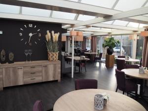 a restaurant with tables and a clock on the wall at Hotel De Zoete Inval Haarlemmerliede in Haarlem