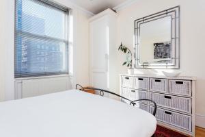 ロンドンにあるヴィーヴ 1ベッドルーム アパートメント イン ザ ウエストエンド メリルボーンの白いベッドルーム(鏡、ベッド付)