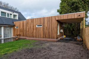 een houten huis met een garage en een hek bij Right Garden Suite in Villa near Centre and TUe in Eindhoven