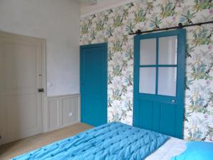 1 dormitorio con puerta azul y papel pintado con motivos florales en Eco Logis de Chantegrolle en Champagne-Mouton