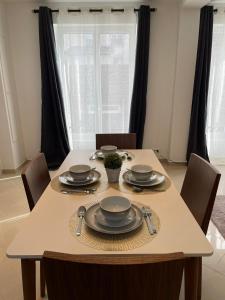 una mesa de comedor con platos y utensilios. en KEYS&HOME L’escapade Parisienne - T2 Cosy & Confort en Le Raincy