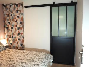 1 dormitorio con puerta negra y cama en Le Richebourg - Charmant T2 Cosy, tout confort, en Gevrey-Chambertin