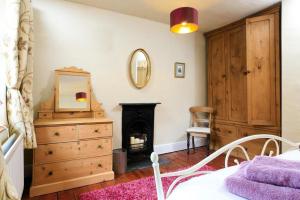 a bedroom with a bed and a dresser and a mirror at Stone Cottage at Staveley in Windermere