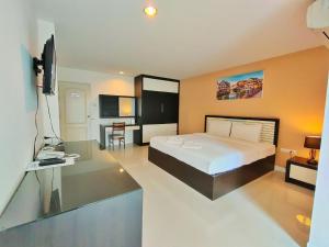 ein Schlafzimmer mit einem Bett, einem Schreibtisch und einem Fernseher in der Unterkunft Similan Mansion in Bangsaen