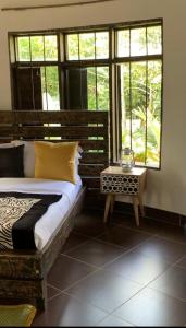 a bedroom with a bed and a table and windows at Mabamba Lodge in Wakiso