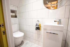 a white bathroom with a toilet and a sink at Nadler House 1 Bed Basement Apartment in Norwich