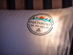 un logotipo al lado de una almohada blanca en Apartamenty na Polnej en Świeradów-Zdrój