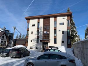 dos autos estacionados frente a un edificio en la nieve en Apartman Mont, Lux & Jacuzzi - Jahorina, en Jahorina
