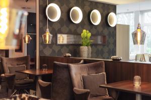 a restaurant with tables and chairs and mirrors on the wall at Select Hotel Hamburg Nord in Hamburg