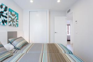 Habitación blanca con cama con almohadas a rayas en Rincón del Duende, en Sevilla