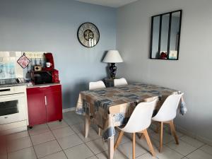 a kitchen with a table with white chairs and a red cabinet at La Rose des Mers in Tréffiagat