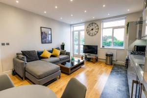 a living room with a couch and a clock on the wall at Thorpe Road 1 Bed Apartment with Parking in Norwich