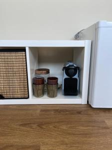 un armario blanco con tres tazas y una estufa en Weltevreden, en Noordwijk