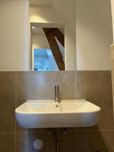 Un lavabo blanco en un baño con espejo. en Weltevreden, en Noordwijk 13 fotos más
