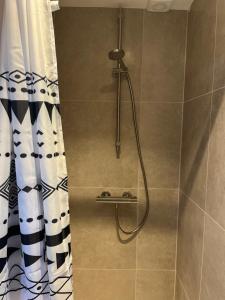 a shower with a shower curtain in a bathroom at Weltevreden in Noordwijk +16 photos