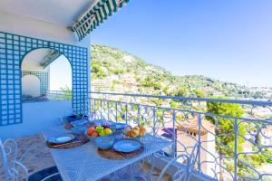 a blue table with bowls of fruit on a balcony at Terrace on the Bay 2 Villefranche-sur-Mer, AP4243 by Riviera Holiday Homes in Villefranche-sur-Mer