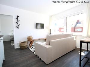 a living room with a white couch and a table at Haus Strandleben in Norderney