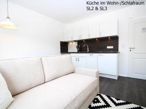 a living room with a white couch in front of a kitchen at Haus Strandleben in Norderney