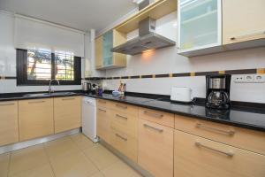 a kitchen with wooden cabinets and black counter tops at Jardines del Pla in Jávea