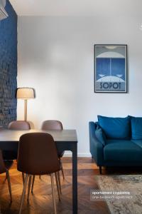 a living room with a blue couch and a table at VIU Apartamenty Modern Retro z parkingiem in Sopot
