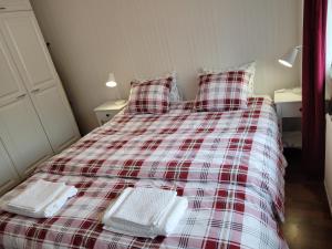 a red and white plaid bed with two white towels on it at Siisti ja kodikas asunnon keskustassa+free parking in Kuopio