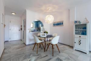 a dining room with a table and white chairs at Beach apartment La Cala in La Cala de Mijas