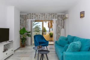 a living room with a blue couch and a tv at Beach apartment La Cala in La Cala de Mijas
