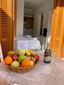 Un bol de fruta sobre una mesa con una botella de vino. en Appartamenti Residence Poseidone, en Santa Teresa Gallura