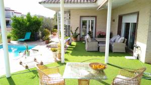 un patio trasero con mesa, sillas y piscina en Villa los Angeles Piscine privée pour 20 personnes, en Sant Mateu