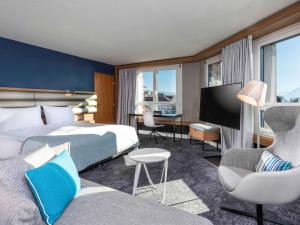 ローザンヌにあるMövenpick Hotel Lausanneのベッドとデスクが備わるホテルルームです。